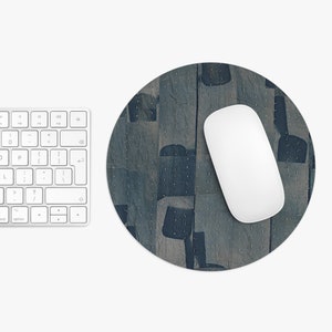 May include: Round mousepad with a blue and gray abstract pattern. A white wireless mouse rests on the pad, next to a white keyboard. The mousepad has a textured appearance.