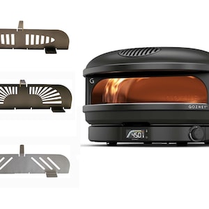 Könnte beinhalten: Ein schwarzer Pizzaofen mit einem digitalen Temperaturdisplay, das 450 Grad Fahrenheit anzeigt. Der Ofen hat eine Glastür und ein Edelstahl-Innenleben. Der Ofen steht auf einer weißen Oberfläche. Drei verschiedene Pizzaofen-Accessoires aus Metall sind auf dem Bild zu sehen.