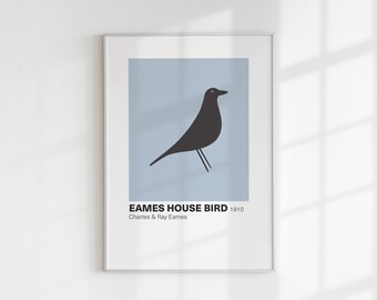 May include: A framed print of a black silhouette of a bird on a light blue background. The print has the text "Eames House Bird 1910 Charles & Ray Eames" at the bottom.