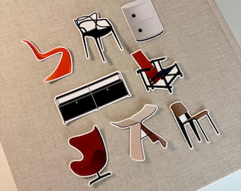 May include: A collection of eight furniture stickers featuring an orange S-shaped chair, a black wire chair, a white cylindrical cabinet, a black rectangular sideboard, a red and black lounge chair, a red egg-shaped chair, a beige stool, and a brown chair.