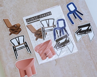 May include: A collection of stickers featuring iconic chair designs. The stickers include various chair styles in shades of brown, blue, black, and pink. The text "ICONIC CHAIRS" is printed on a white background.