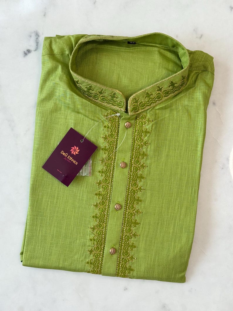 May include: A lime green kurta shirt with detailed embroidery on the collar and front. The shirt features a mandarin collar and gold buttons. A tag from "Desi Ethnics" is attached to the garment.