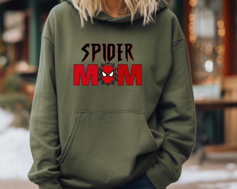 May include: A green hooded sweatshirt with the text "SPIDER MOM" in black and red lettering. A red spider-man face is in the center of the text.