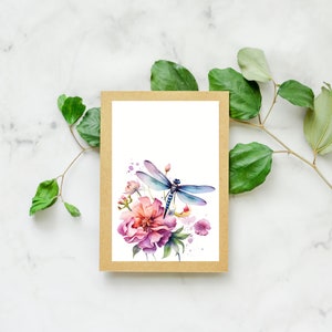 Puede incluir: Una ilustraci&oacute;n de acuarela de una lib&eacute;lula posada sobre una flor rosa con hojas verdes. La ilustraci&oacute;n est&aacute; impresa en una tarjeta blanca y enmarcada con un borde marr&oacute;n.