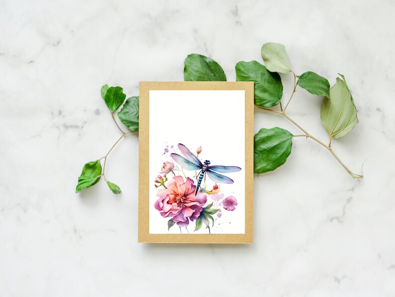 Puede incluir: Una ilustraci&oacute;n de acuarela de una lib&eacute;lula posada sobre una flor rosa con hojas verdes. La ilustraci&oacute;n est&aacute; impresa en una tarjeta blanca y enmarcada con un borde marr&oacute;n.