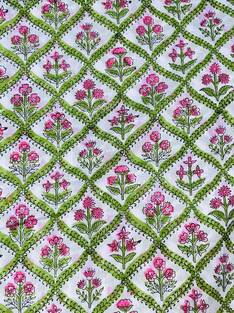 Puede incluir: Tela blanca con un patr&oacute;n repetido de flores rosas y bordes verdes en forma de diamante. El dise&ntilde;o floral incluye varias formas de flores, creando un patr&oacute;n textil visualmente atractivo. Adecuado para proyectos de costura y artesan&iacute;a.