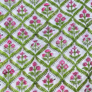 May include: White fabric with a repeating pattern of pink and green flowers in a diamond shape.