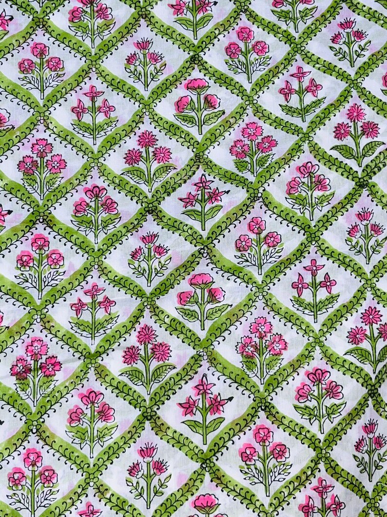 May include: White fabric with a repeating pattern of pink and green flowers in a diamond shape.