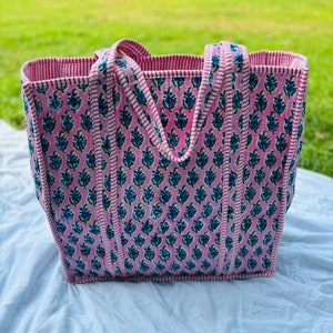 May include: A pink and white striped tote bag with a floral pattern. The bag has two handles and is made of a sturdy fabric.