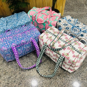 May include: A collection of colorful, patterned travel bags. The bags feature floral and geometric designs in shades of blue, pink, purple, and white. Each bag has a matching handle.