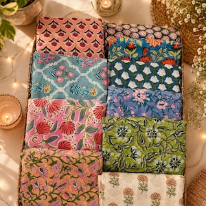 May include: A rectangular woven basket filled with ten folded fabric squares featuring various floral block print patterns in colors including pink, blue, green, orange, and white. Each piece of fabric displays a distinct botanical motif.