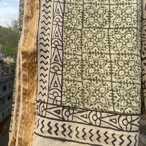May include: A cream-colored cotton fabric with a green and black block print design. The fabric has a gold border.