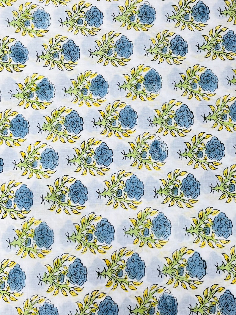May include: White fabric with a repeating pattern of blue flowers with yellow and green leaves.