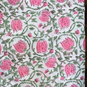 May include: White fabric with a pink and green floral print. The pattern features pink flowers with green leaves and vines.