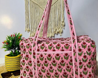 May include: Pink floral print travel duffel bag with white and pink striped straps. The bag has a quilted design and is made of cotton.