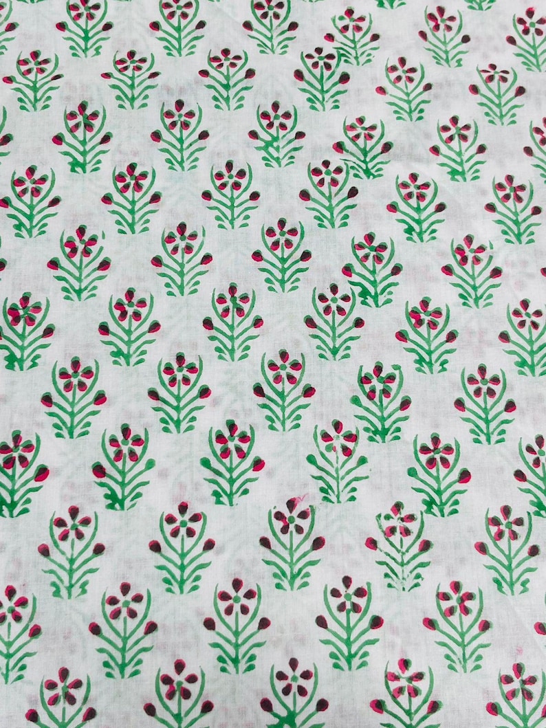 May include: White fabric with a repeating pattern of green and pink stylized flowers.
