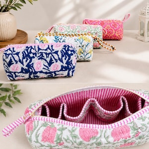 May include: A collection of four quilted fabric pouches featuring floral block print patterns in blue, white, yellow, and pink. The pouches have zippered closures and wrist straps. One open pouch reveals a pink and white striped interior lining.