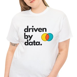 Peut inclure: T-shirt blanc avec l'inscription "driven by data." en noir et un graphisme de deux cercles qui se chevauchent en jaune, rouge et turquoise. Vêtement décontracté.