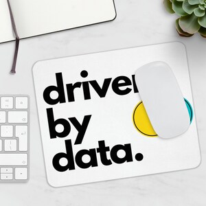 May include: White mouse mat with black text that reads "driven by data." There are two small circles, one yellow and one blue, on the mouse mat.