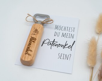May include: A wooden bottle opener with the text "Patenonkel" engraved on it. A card with the text "Möchtest du mein Patenonkel sein?" is next to the bottle opener.