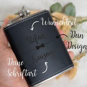 Könnte beinhalten: Schwarze, lederbezogene Trinkflasche mit silbernem Verschluss und graviertem Text "Stefan" mit Fliege und "Trauzeuge" darunter. Der Text "Dein Design" und "Deine Schriftart" ist in Kursivschrift auf dem Bild geschrieben.