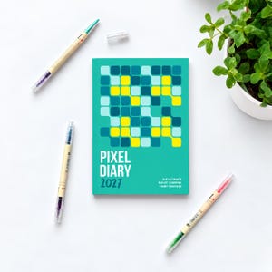 May include: A teal 2027 Pixel Diary bullet journal habit tracker with a grid of yellow, light blue, and dark blue squares on the cover. The text reads PIXEL DIARY 2027 THE ULTIMATE BULLET JOURNAL HABIT TRACKER. Three dual-tip markers are placed nearby.