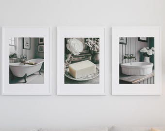 May include: Three framed black and white photographs of a bathroom with a clawfoot tub, a bar of soap on a plate, and a white porcelain sink. The frames are white and have a simple design.