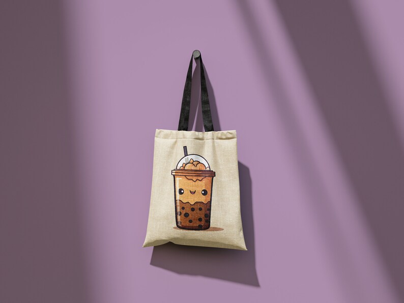 May include: A beige tote bag with black handles hangs against a purple wall. The bag features a cartoon illustration of a brown bubble tea drink with a smiling face. The drink has a clear lid and a straw.