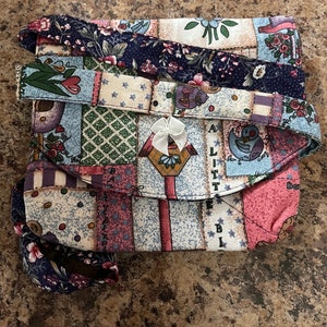 May include: A patchwork fabric purse with a floral print and a white bow. The purse has a flap closure and a strap.