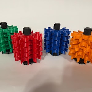 May include: Four colorful, 3D-printed objects in green, red, blue, and orange. Each has a cylindrical shape with a black top and a base. The objects are arranged on a white surface.