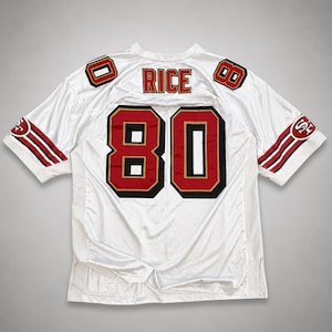 Pode incluir: Camisola de futebol branca com o número 80 em vermelho e dourado, e o nome "RICE" nos ombros. A camisola tem riscas vermelhas e brancas nas mangas e ombreiras. A camisola é feita de um material respirável e perfurado.