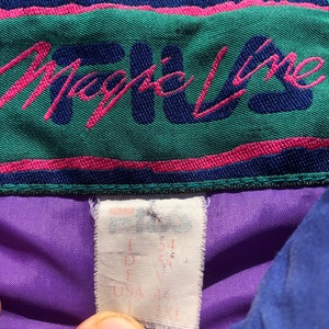 May include: Purple and blue jacket with a green and pink label that says "Magic Line". The label has a white tag attached with the size written on it.