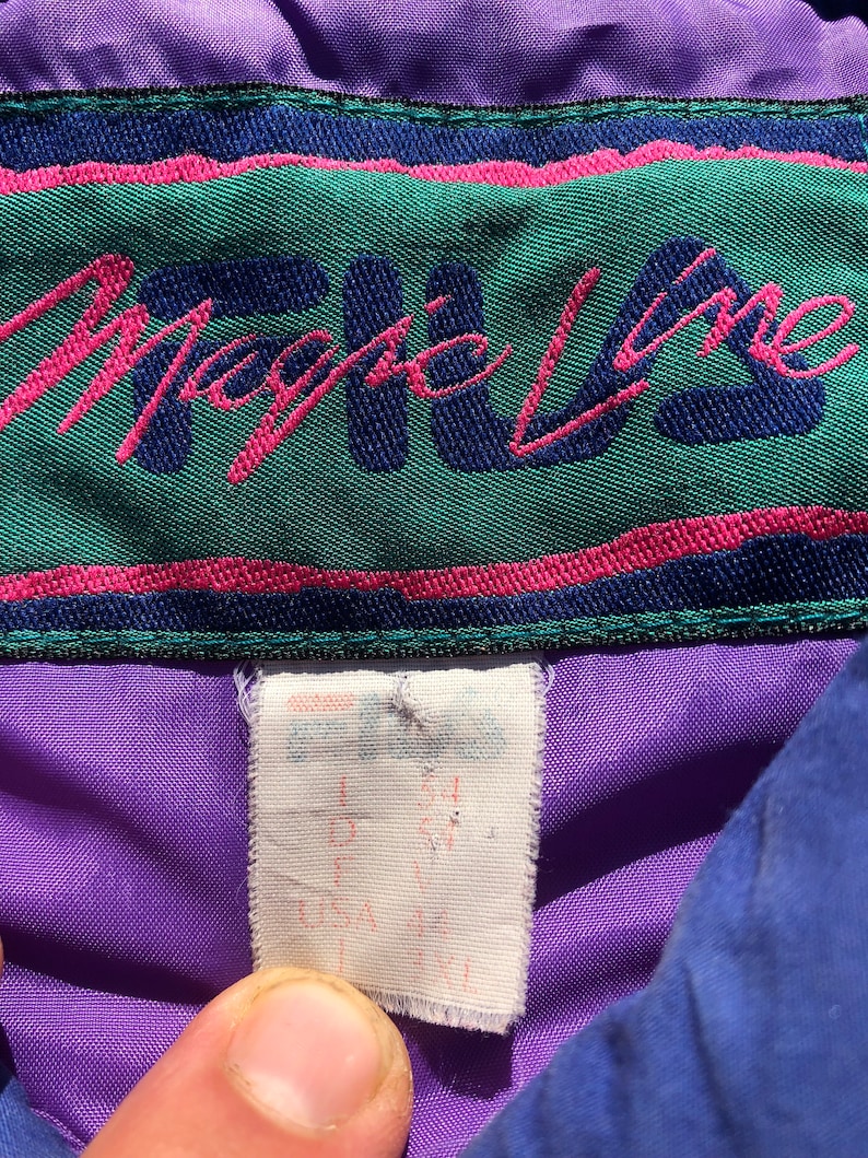 May include: Purple and blue jacket with a green and pink label that says "Magic Line". The label has a white tag attached with the size written on it.