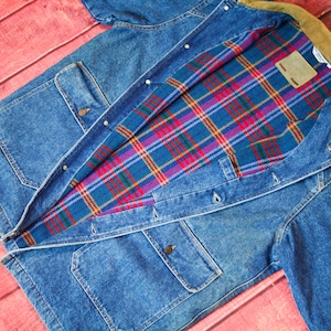 May include: A blue denim jacket with a plaid flannel lining. The jacket has a corduroy collar and multiple pockets.
