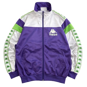 Könnte beinhalten: Eine lila, weiße und grüne Kappa-Trainingsjacke mit durchgehendem Reißverschluss. Die Jacke hat das Kappa-Logo auf der Brust und grüne und weiße Streifen an den Ärmeln. Sie hat einen Stehkragen.