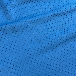 K&ouml;nnte beinhalten: Nahaufnahme eines leuchtend blauen Mesh-Stoffs. Der Stoff hat ein gleichm&auml;&szlig;iges Muster aus kleinen, gleichm&auml;&szlig;ig verteilten L&ouml;chern, wodurch eine atmungsaktive Textur entsteht. Die Farbe ist ein helles, sattes Blau mit subtilen Farbtonvariationen.