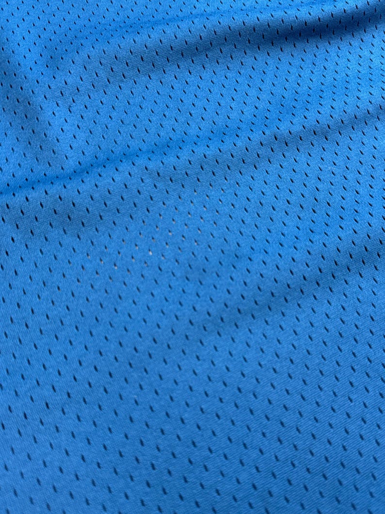 K&ouml;nnte beinhalten: Nahaufnahme eines leuchtend blauen Mesh-Stoffs. Der Stoff hat ein gleichm&auml;&szlig;iges Muster aus kleinen, gleichm&auml;&szlig;ig verteilten L&ouml;chern, wodurch eine atmungsaktive Textur entsteht. Die Farbe ist ein helles, sattes Blau mit subtilen Farbtonvariationen.