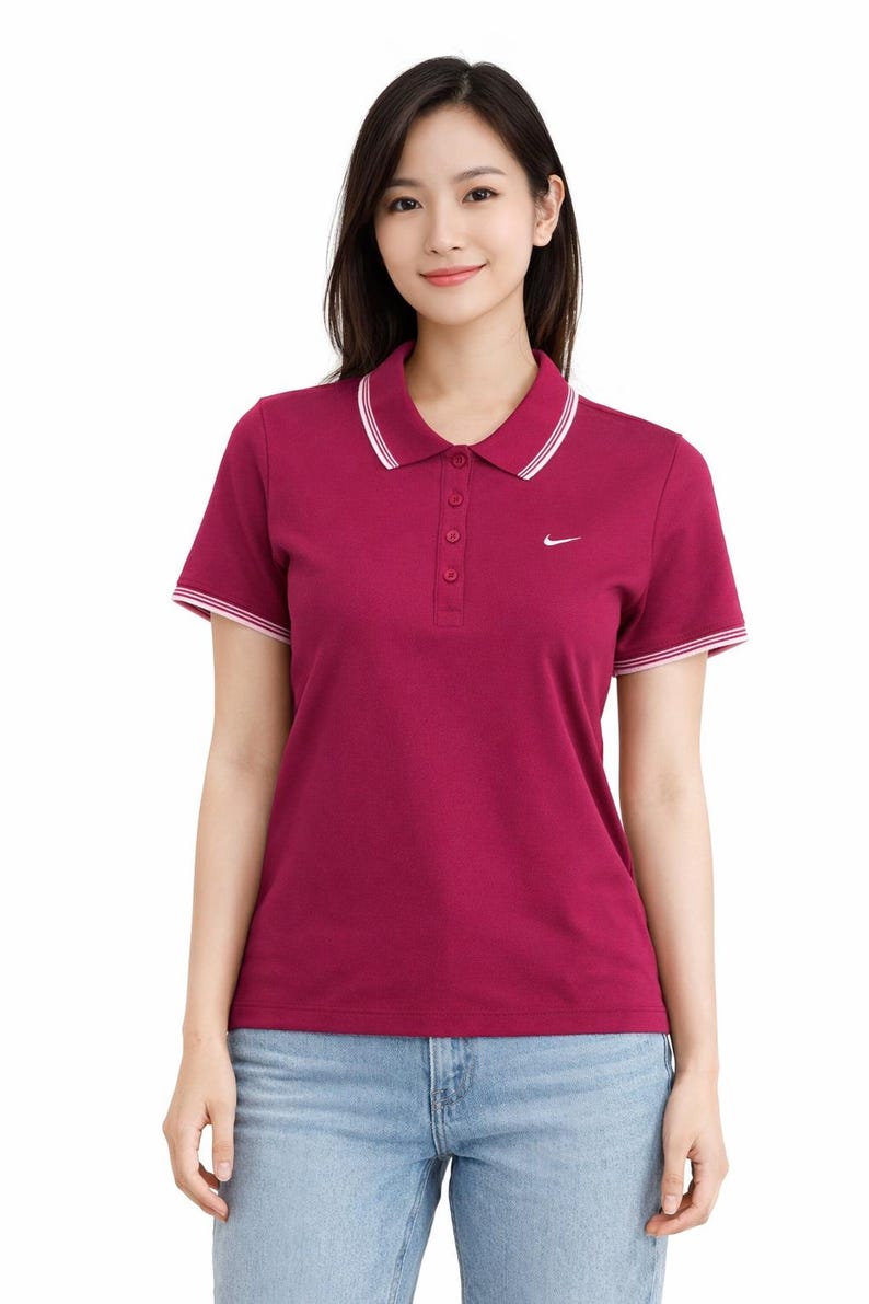 May include: A maroon polo shirt with a white collar and sleeve trim. The shirt has a three-button placket and a small white Nike logo on the chest. The model is wearing blue jeans.
