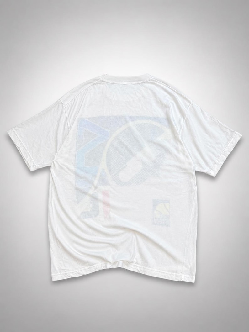 May include: White t-shirt with a colorful graphic design on the back. The graphic features a geometric pattern with blue, red, and yellow accents. The shirt is made of a soft, lightweight material, perfect for casual wear.