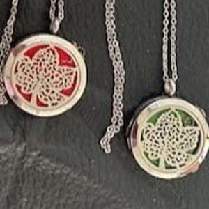 May include: Three silver tree-shaped essential oil diffusers with a chain. The diffusers are oval-shaped and have a red, green, and black background.