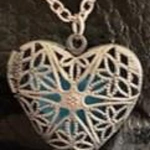 May include: Silver heart-shaped locket with a delicate filigree design and a blue and white stone in the center.