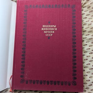 Op de afbeelding: Een rood hardback boek met een zwarte rand en de tekst "ШЕДЕВРЫ ЖИВОПИСИ МУЗЕЕВ СССР" op de voorkant.