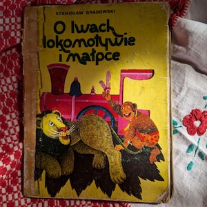 以下が含まれることがあります： 黄色い表紙のヴィンテージポーランドの子供向けの本。表紙のイラストは、ライオン、猿、赤い列車を描いています。本のタイトルはポーランド語です。表紙は使用感があります。