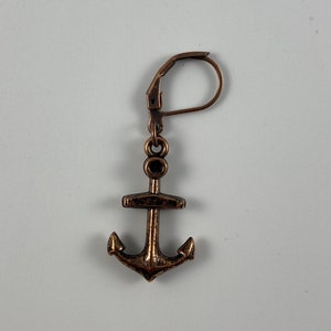 May include: A single bronze-colored anchor earring with a lever-back closure. The anchor charm features a detailed design with a textured finish. The earring is designed for pierced ears and is displayed against a white background.