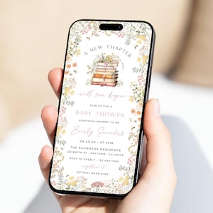 Puede incluir: Un teléfono inteligente muestra una invitación a un baby shower. El diseño presenta elementos florales y el texto "Un nuevo capítulo comenzará pronto". La invitación incluye detalles para el baby shower de Everly Saunders.