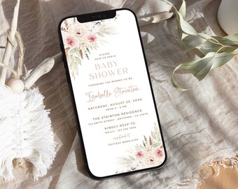May include: A smartphone screen shows a baby shower invitation with floral decorations. The invitation includes the words "Baby Shower", the name "Isabelle Stainton", and event details. The phone is on a textured surface.