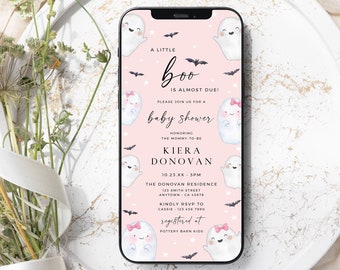 Puede incluir: Una pantalla de teléfono inteligente muestra una invitación a un baby shower con un fondo rosa e ilustraciones de fantasmas. El texto dice "A Little Boo is Almost Due!" e incluye detalles del evento, como el nombre, la fecha, la hora y el lugar.