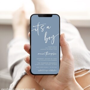 May include: A blue and white baby shower invitation on a smartphone screen. The invitation reads "It's a boy" and includes the name "maeve thompson". The invitation also includes the date, time, and location of the baby shower.