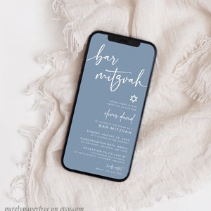 May include: A smartphone displays a Bar Mitzvah invitation. The invitation features elegant white script on a dusty blue background, with a Star of David symbol. The text includes the name Oliver David, date, time, and location details.