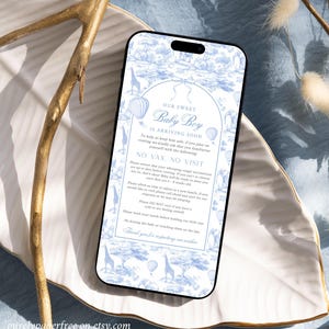 May include: A smartphone displaying a baby shower announcement with a blue and white toile design. The text reads "Our Sweet Baby Boy Is Arriving Soon" with additional guidelines for visitors. The phone rests on a decorative white and gold tray.